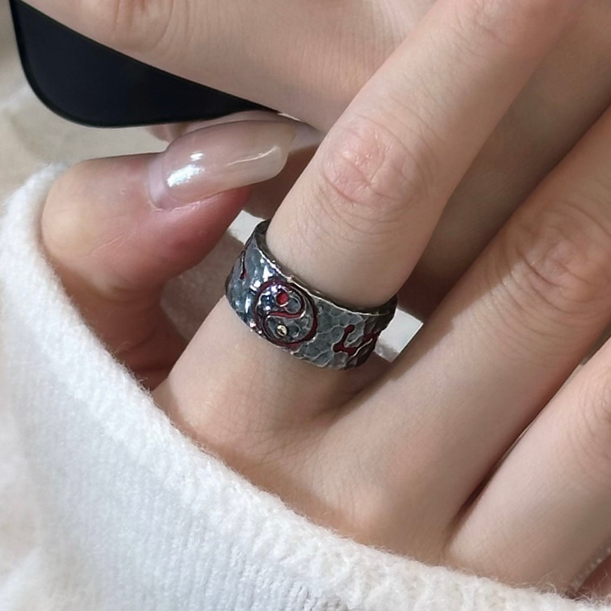 TaoWards yin-yang ring worn with a white knit sleeve