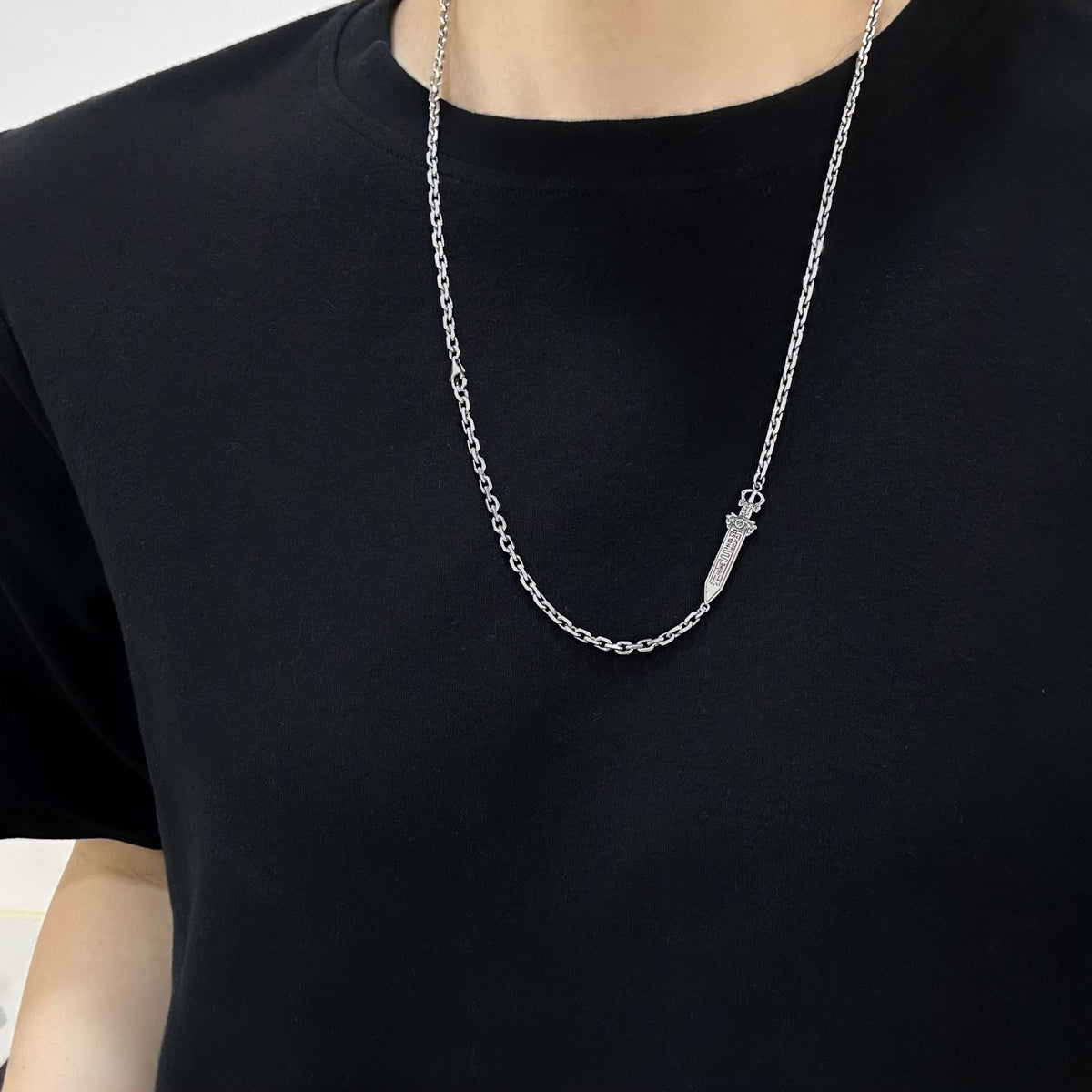 TaoWards sword chain necklace worn over a black T-shirt, with the sword detail slightly to one side.