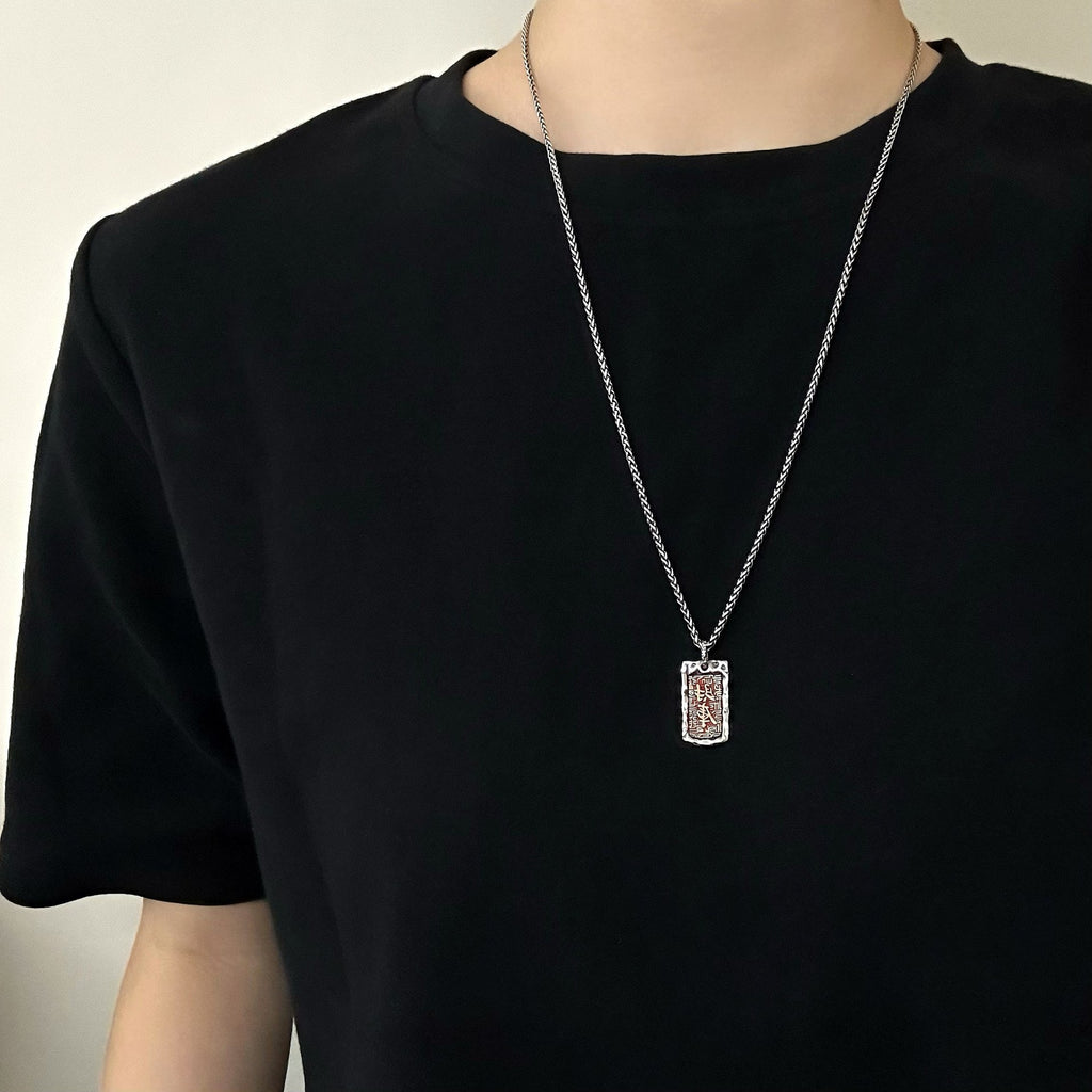 Red tag pendant worn with a black T-shirt; chain not included