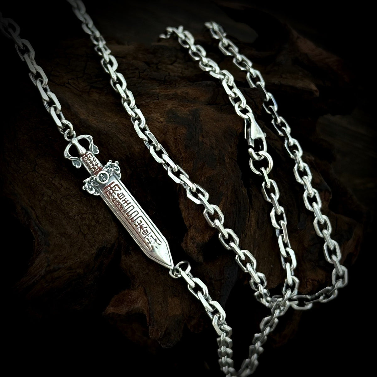 Reverse side of the TaoWards sword chain necklace, showing recessed symbolic patterns.