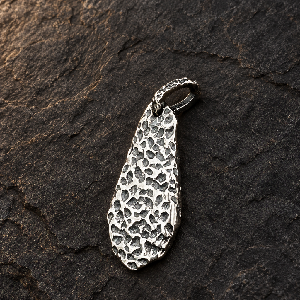 Textured reverse of TaoWards teardrop pendant on a charcoal background