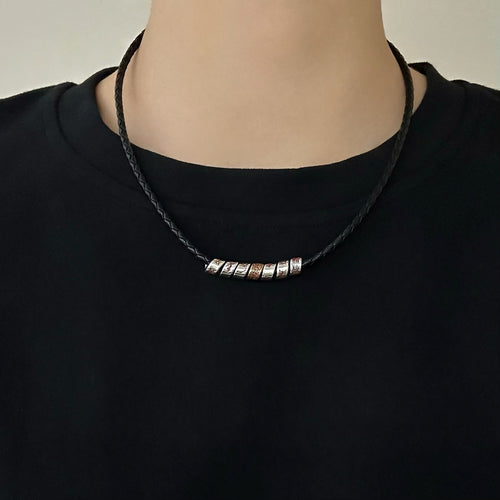 TaoWards black braided cord necklace worn over a black crewneck shirt