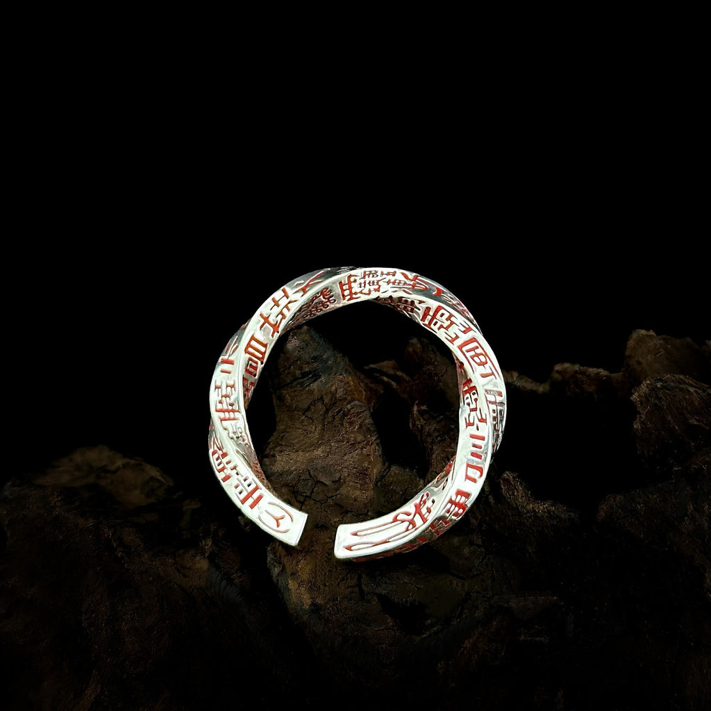Single TaoWards twisted open ring with red engraving on dark wood